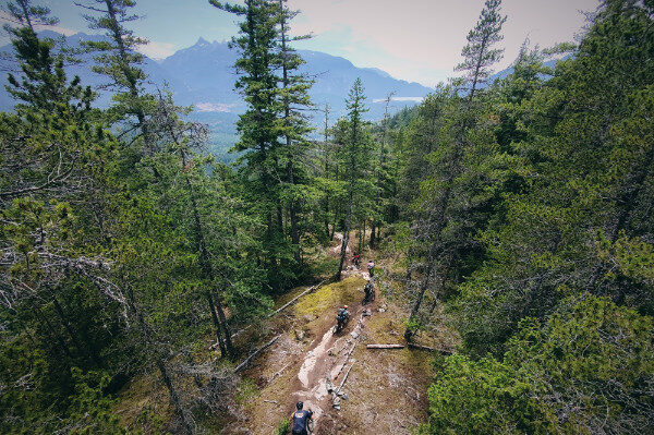 mountain bikers riding on a trail with a big mountain view in the background. Squamish, BC