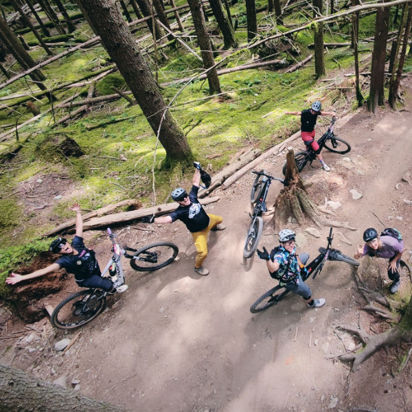 mountain bikers in the forest looking up and posing for a drone camera